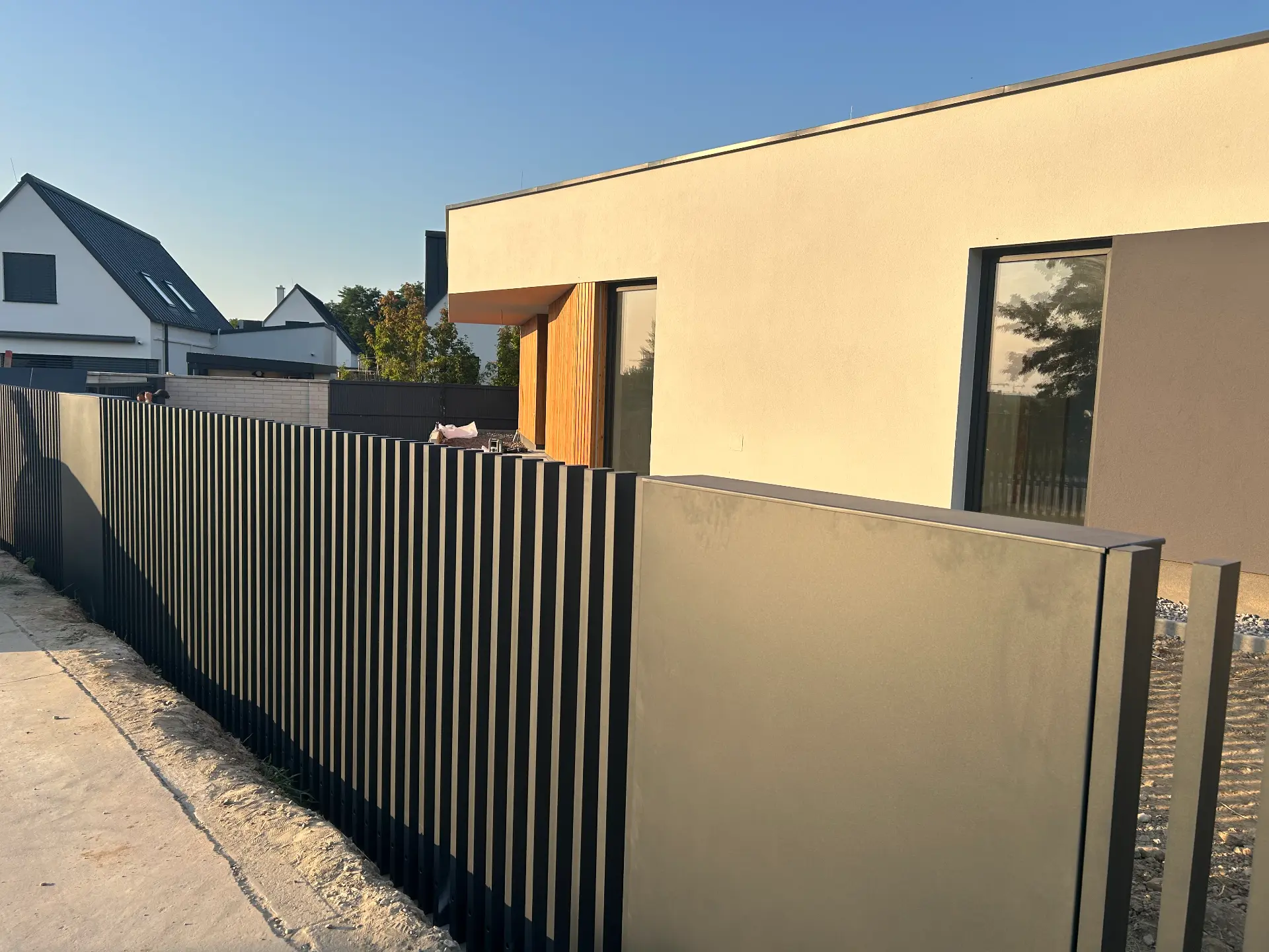 Antracitový lamelový plot vedený pozdĺž moderného rodinného domu