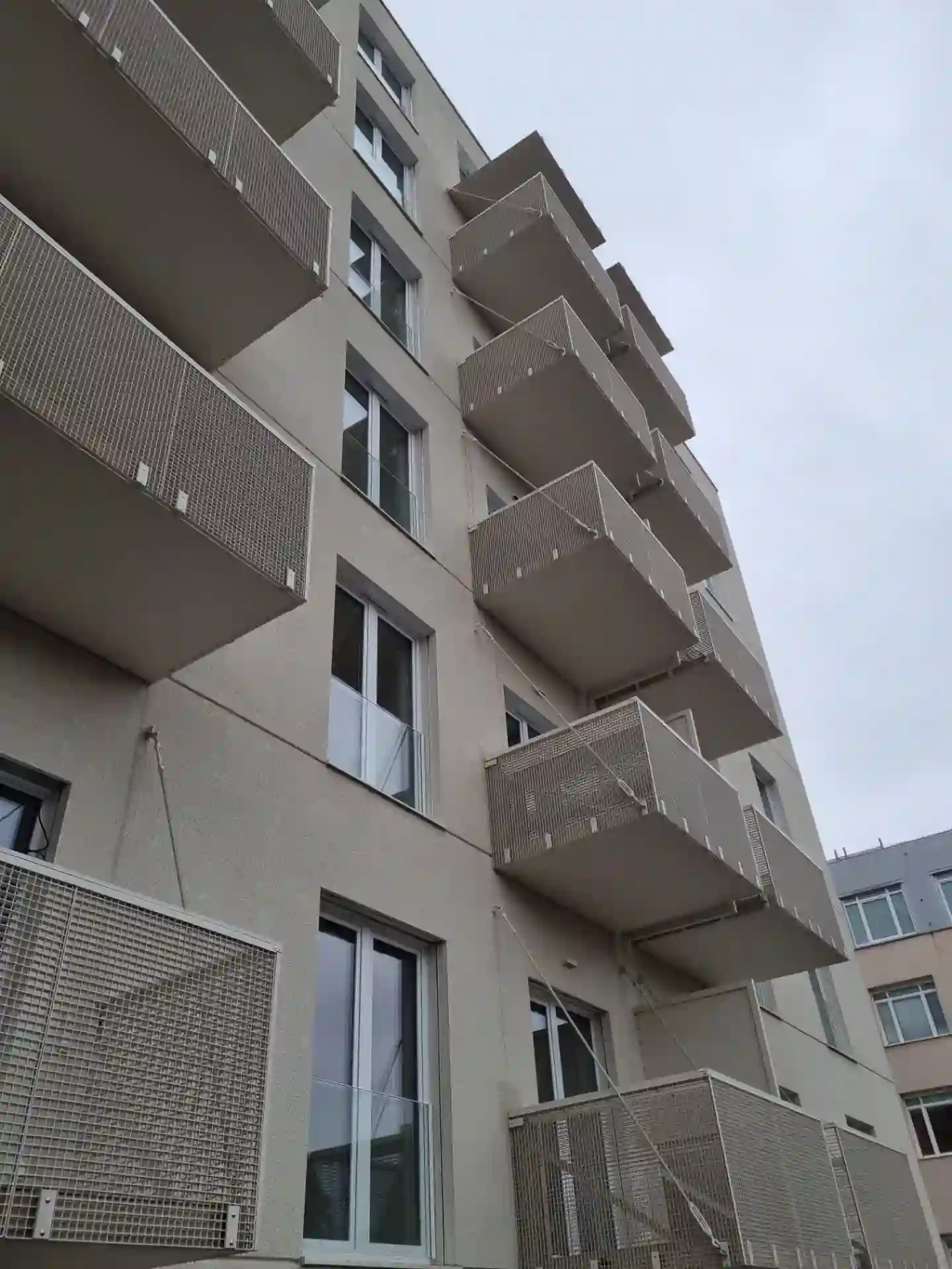 Pohľad zdola na závesné balkóny s ťahokovovými výplňami