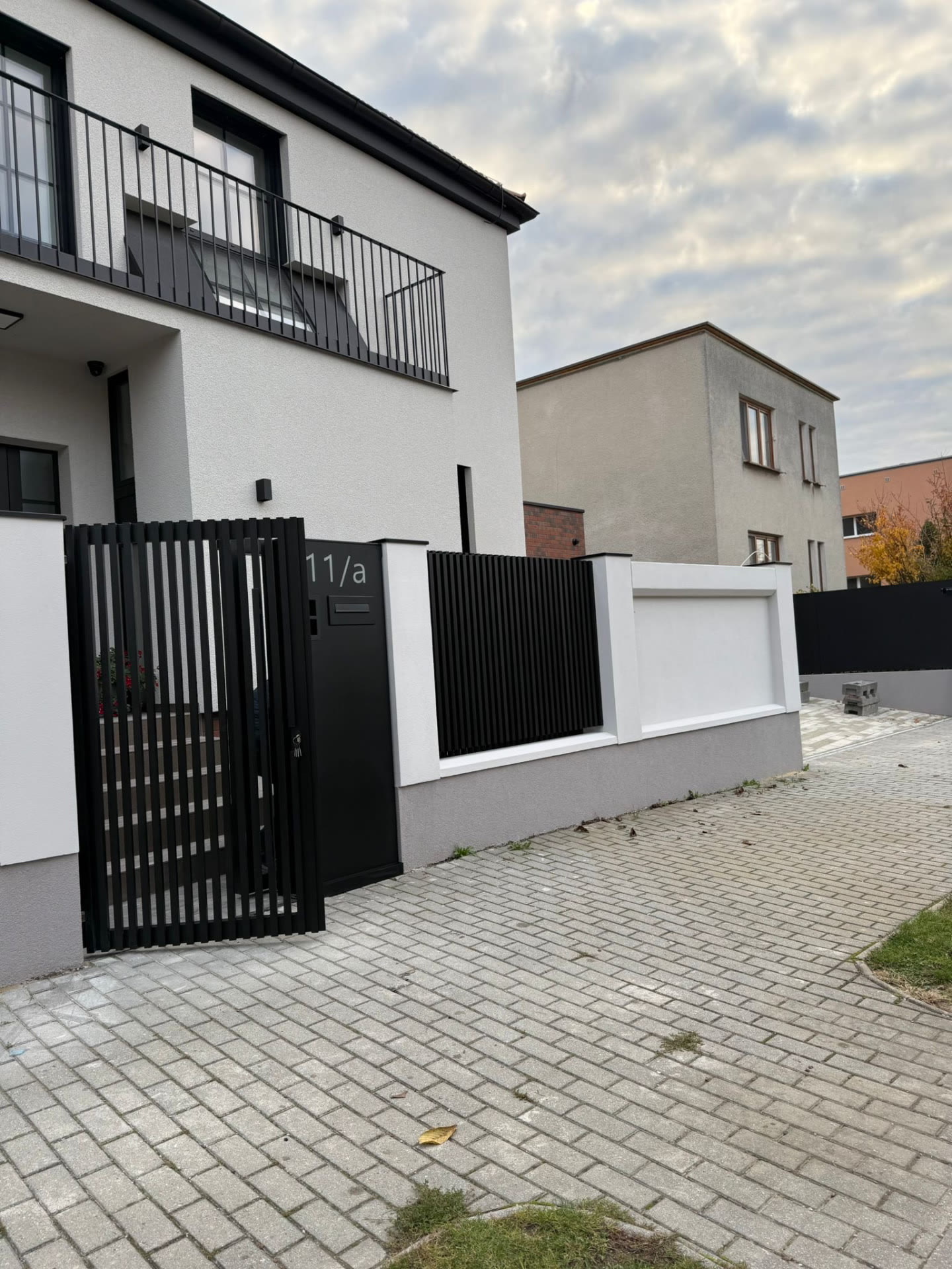 Čierna lamelová bránka s poštovou schránkou a domovým číslom 11/a