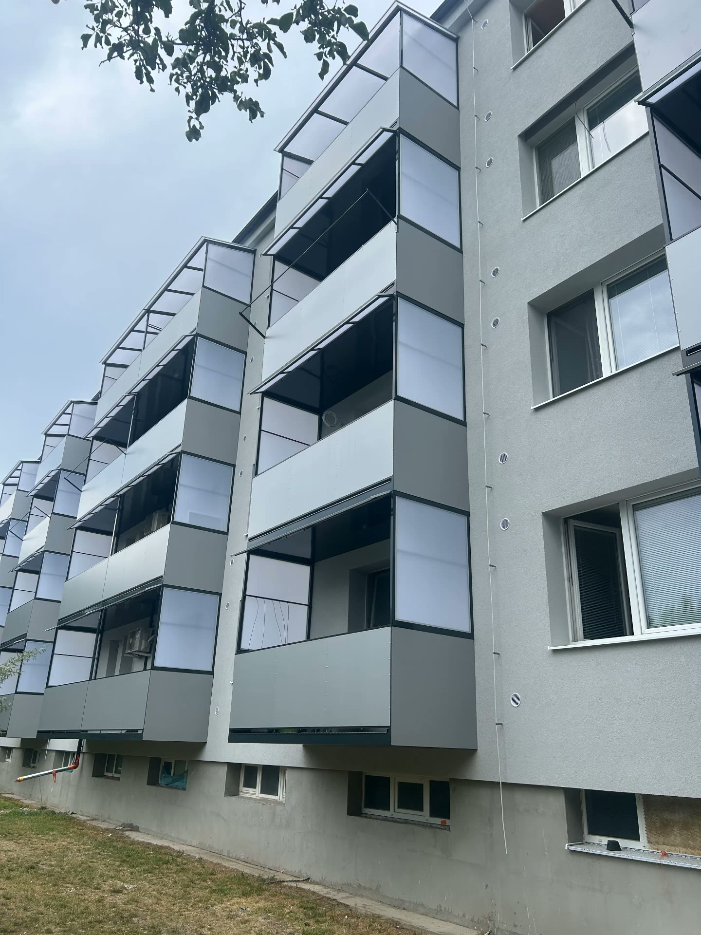Sivé hliníkové balkóny so zasklením na obnovenom bytovom dome