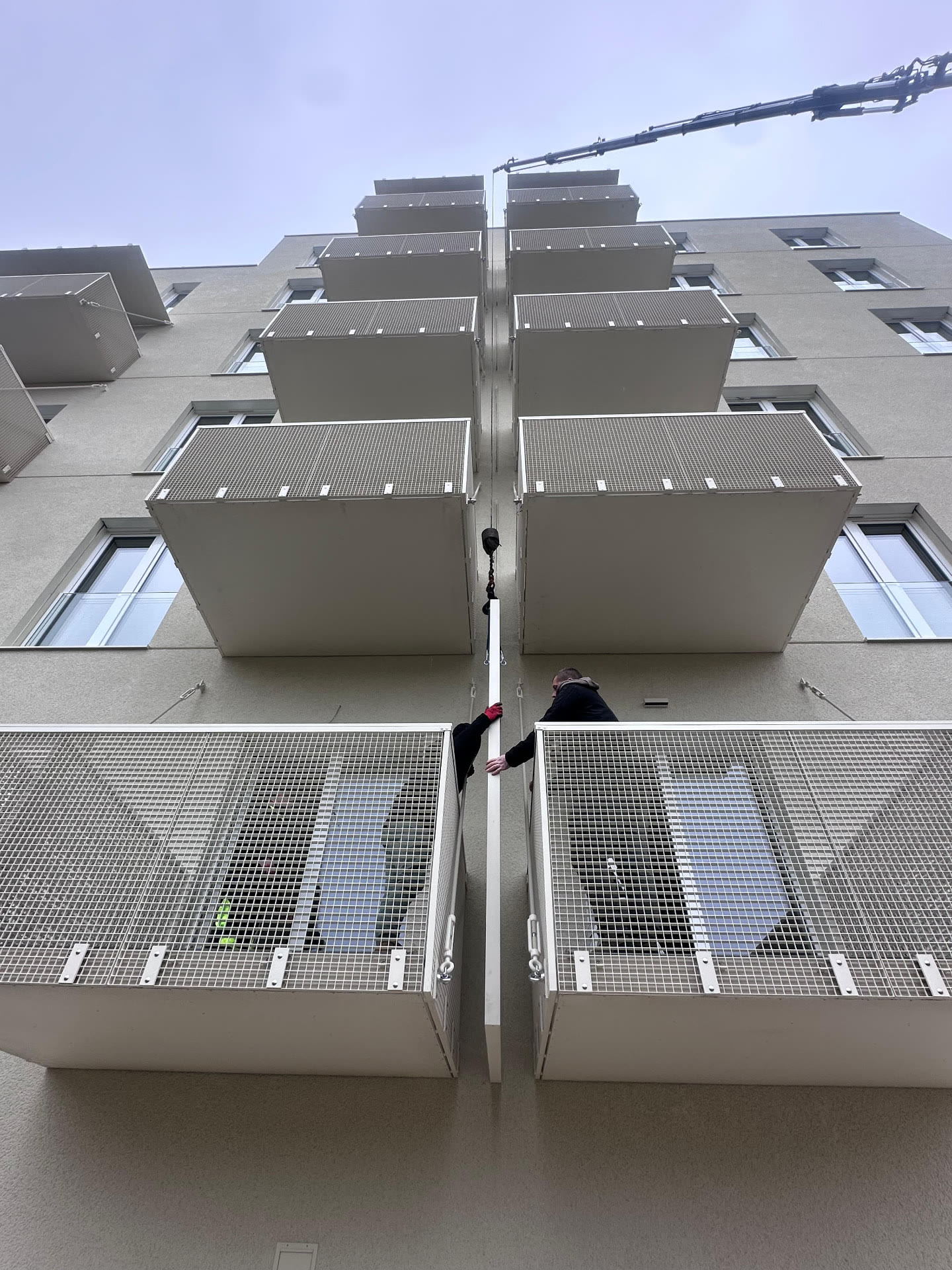 Montáž predsadených hliníkových balkónov na bytovom dome pomocou žeriavu