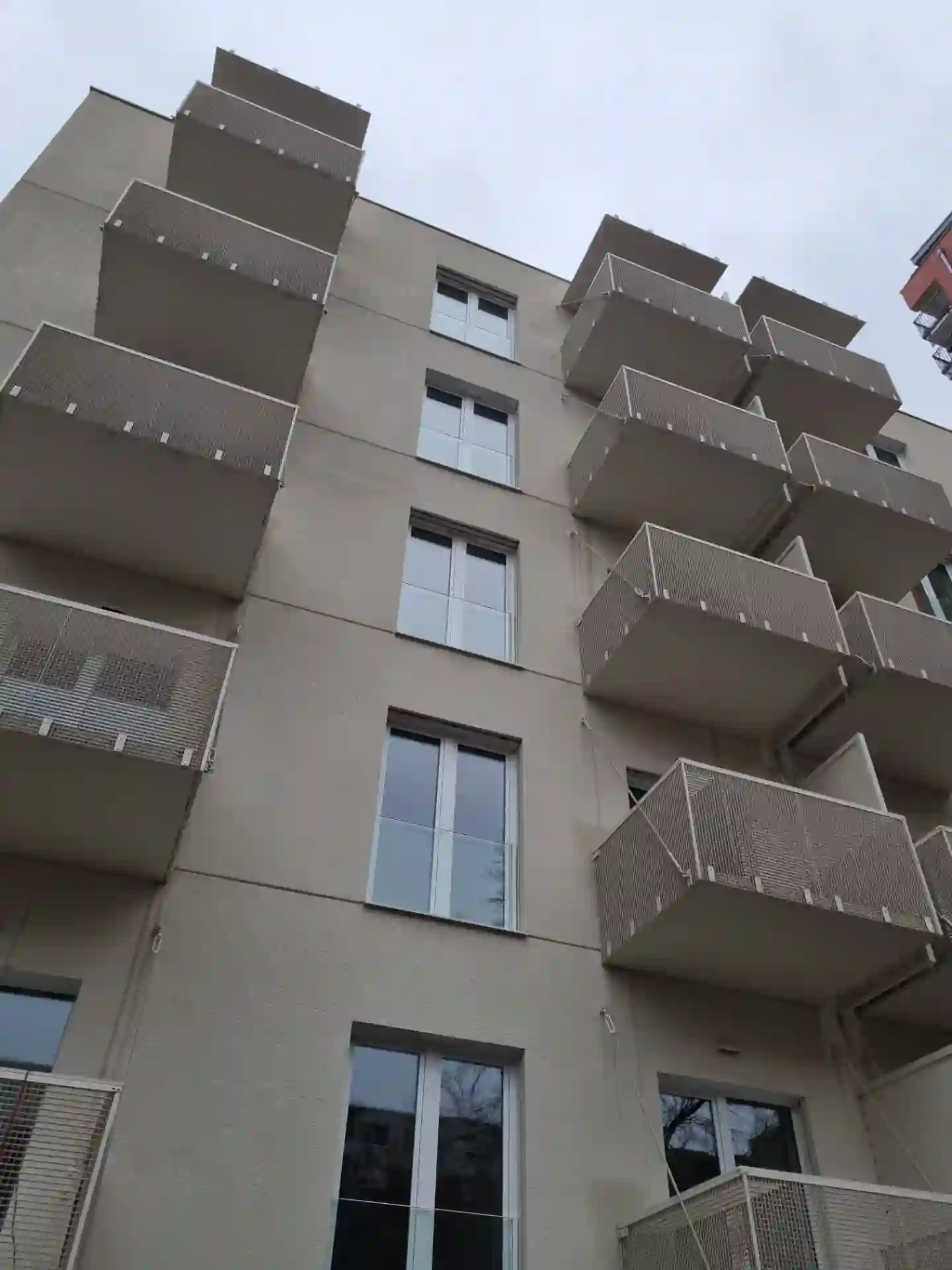 Dva rady balkónov s ťahokovovým zábradlím na svetlej fasáde
